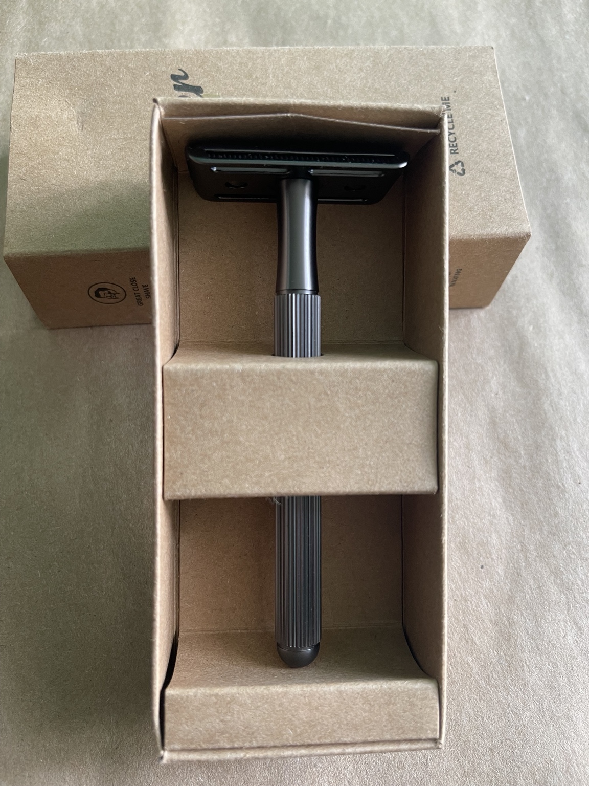 Black safety razor inside its open cardboard box