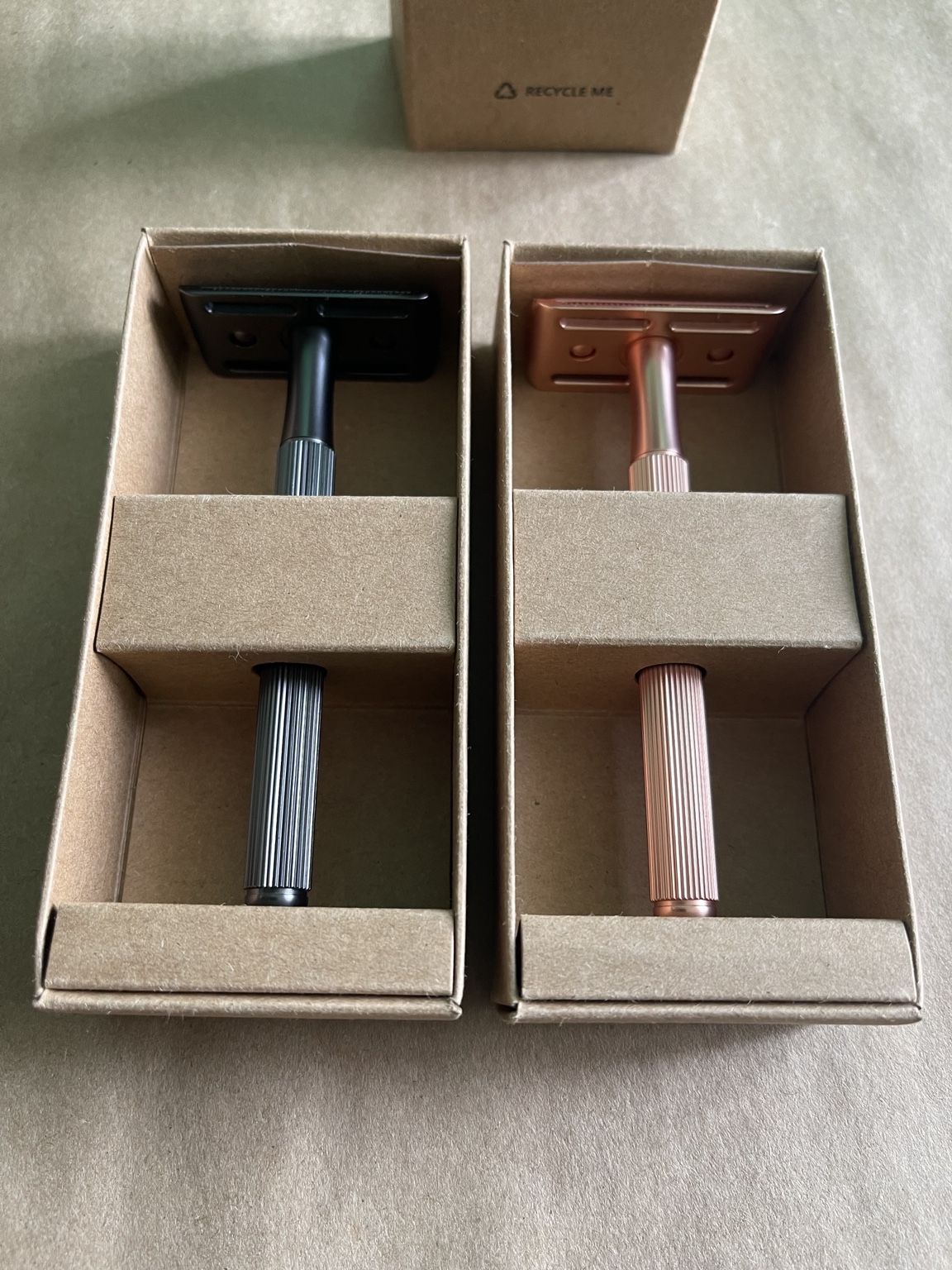 Black and rose-gold safety razors side by side in their open boxes